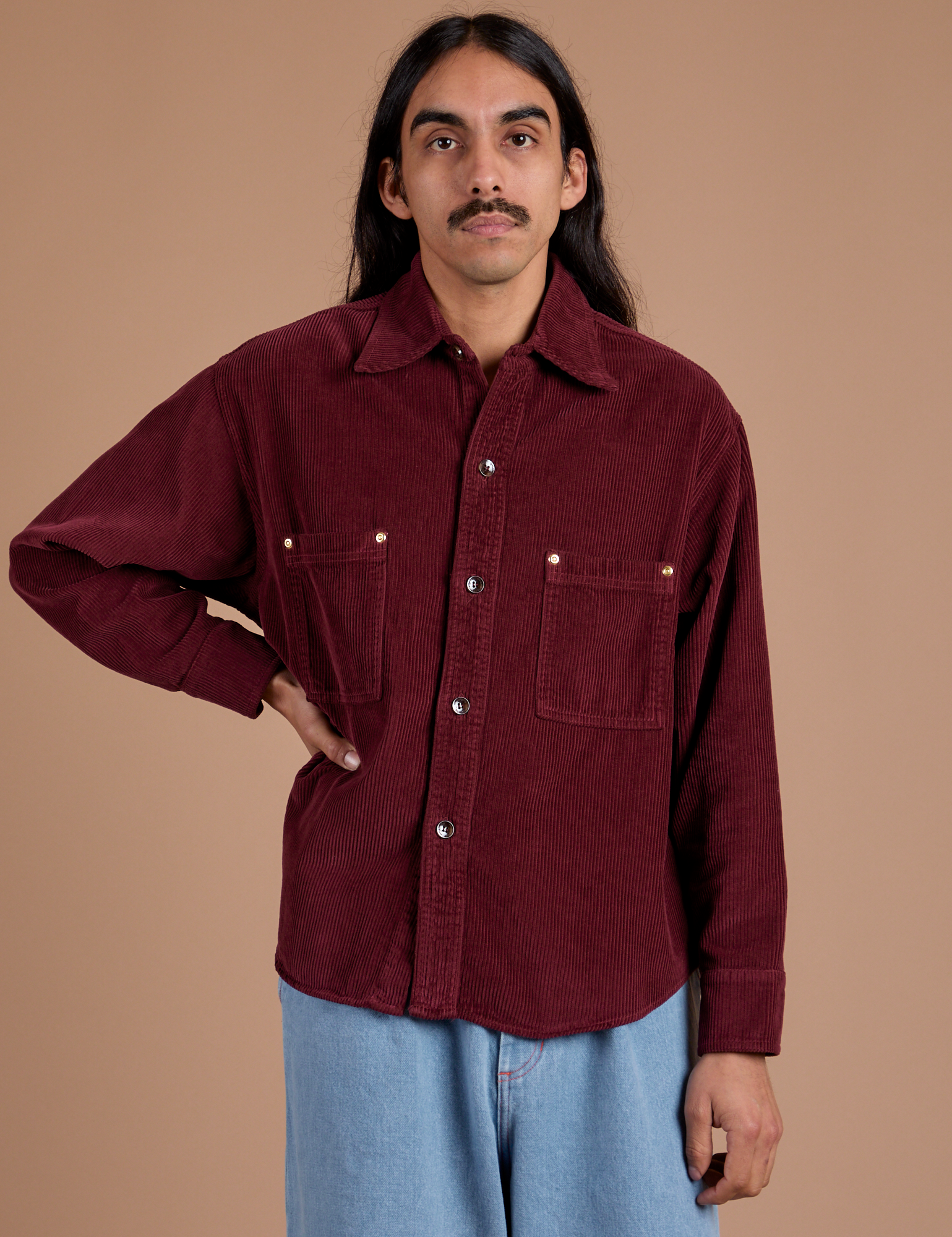 Anthony is wearing a buttoned up Cropped Corduroy Overshirt in Red Wine