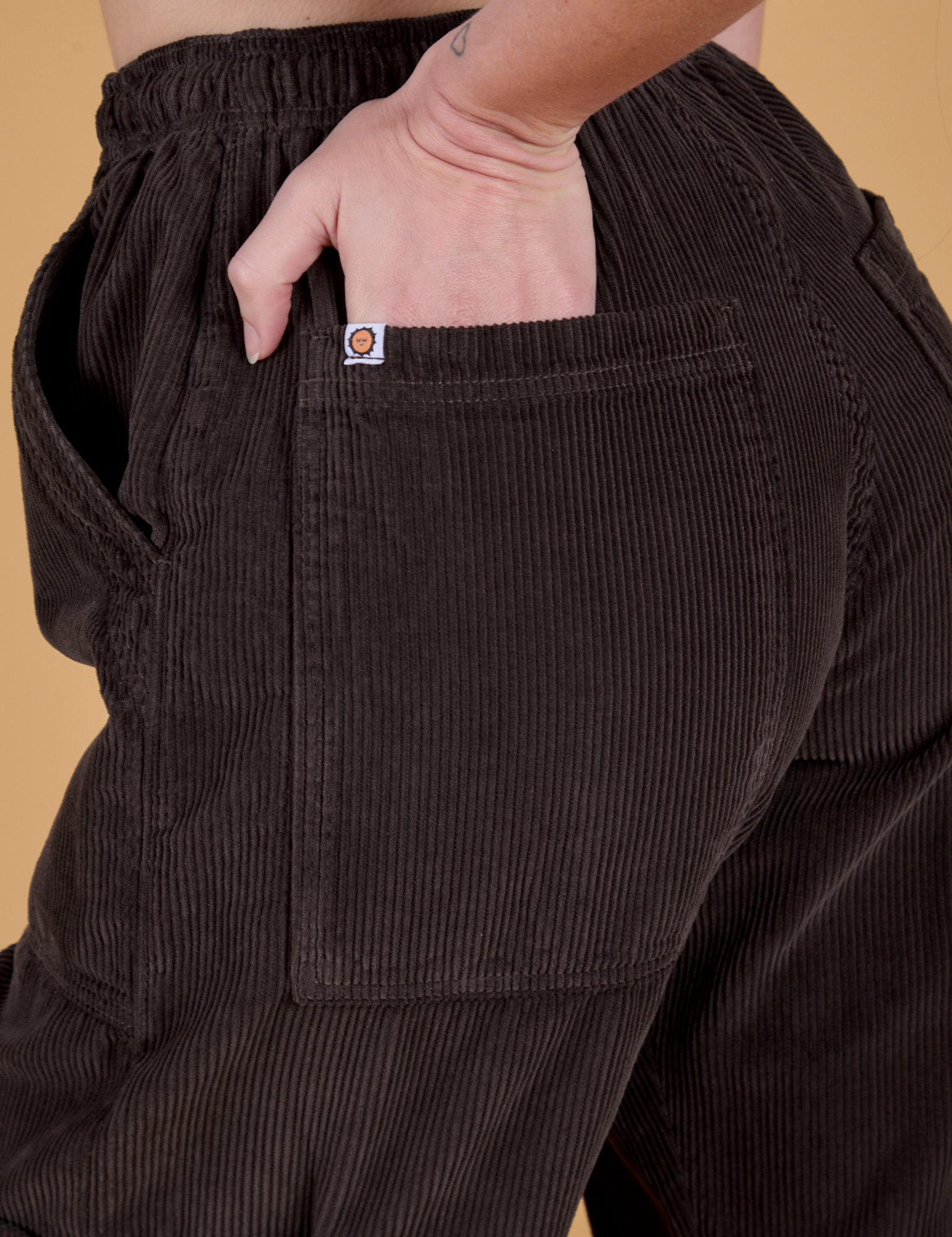 Close up of Alex's hand in the back pocket of Corduroy Drop Pocket Cargo Pants in Espresso Brown