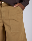Close up of Isaac's hand in the back pocket of Longline Work Shorts in Desert Brown