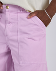 Close up of Isaac's hand in the front pocket of Longline Work Shorts in Lilac Purple