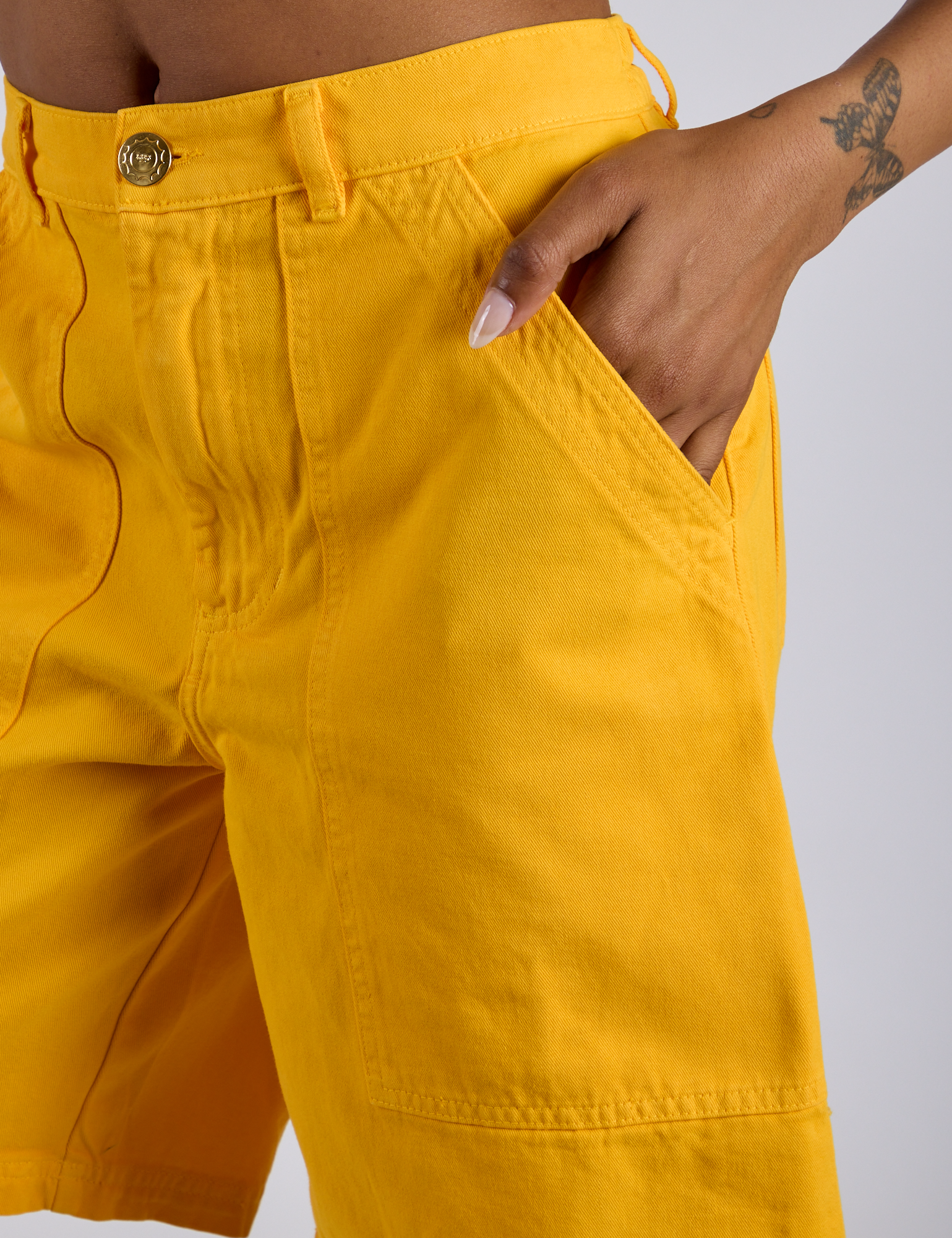 Close up of Kira's hand in the front pocket of Longline Work Shorts in Sunshine Yellow 