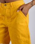 Close up of Kira's hand in the front pocket of Longline Work Shorts in Sunshine Yellow 
