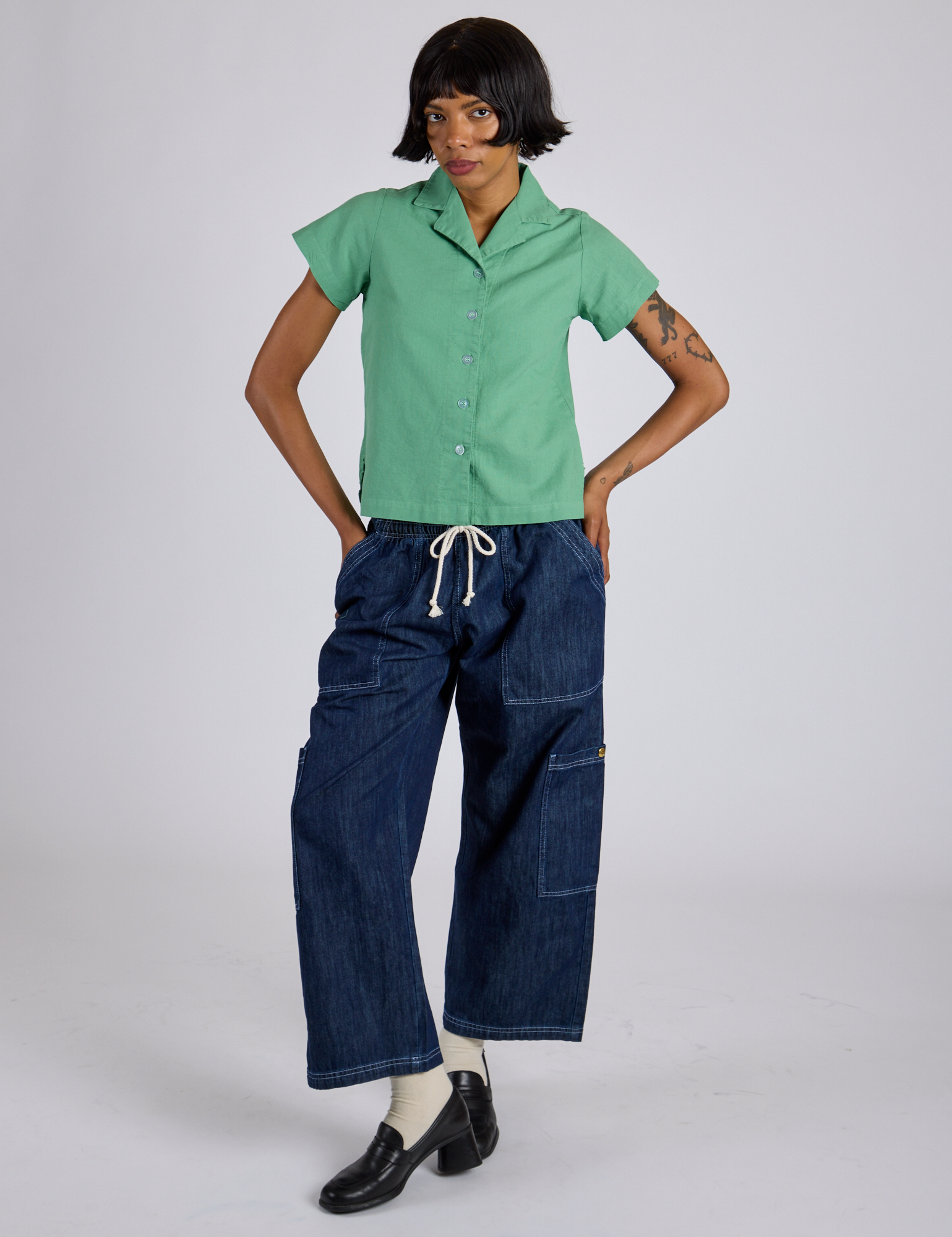 Kira is 5’10” and wearing P Pantry Button-Up in Seafoam Green paired with dark wash Denim Drop Pocket Pants