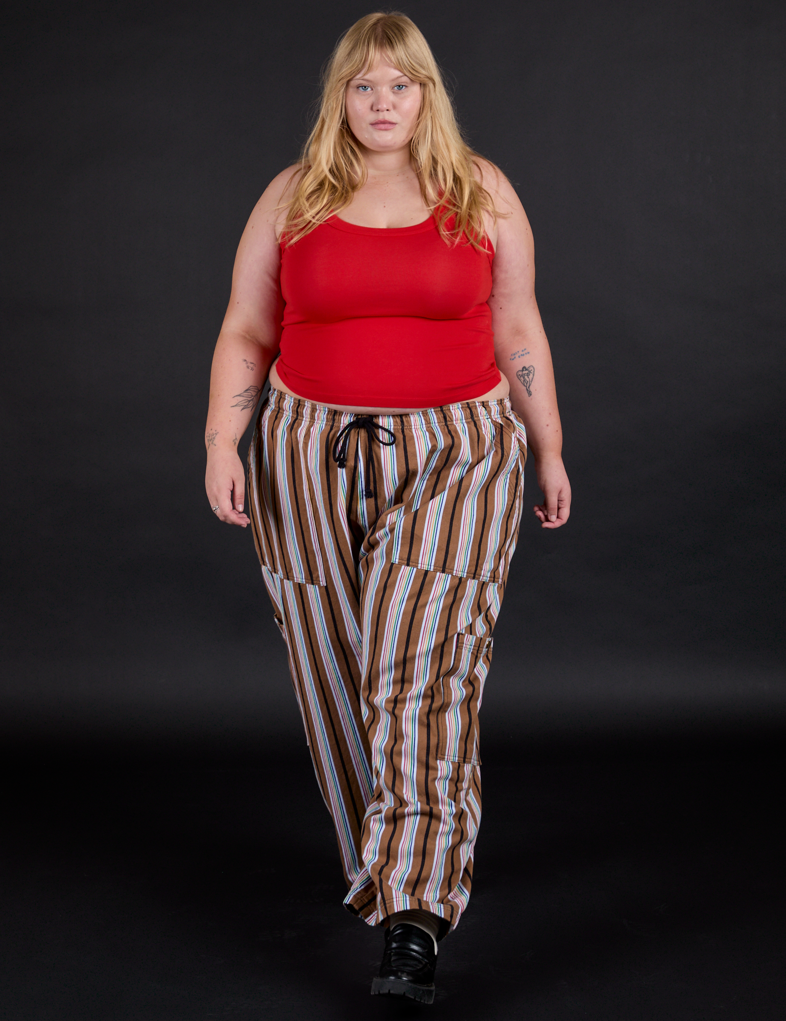 Juliet is 5'7" and wearing 1XL Striped Drop Pocket Pants in Retro Rainbow paired with mustang red Tank Top