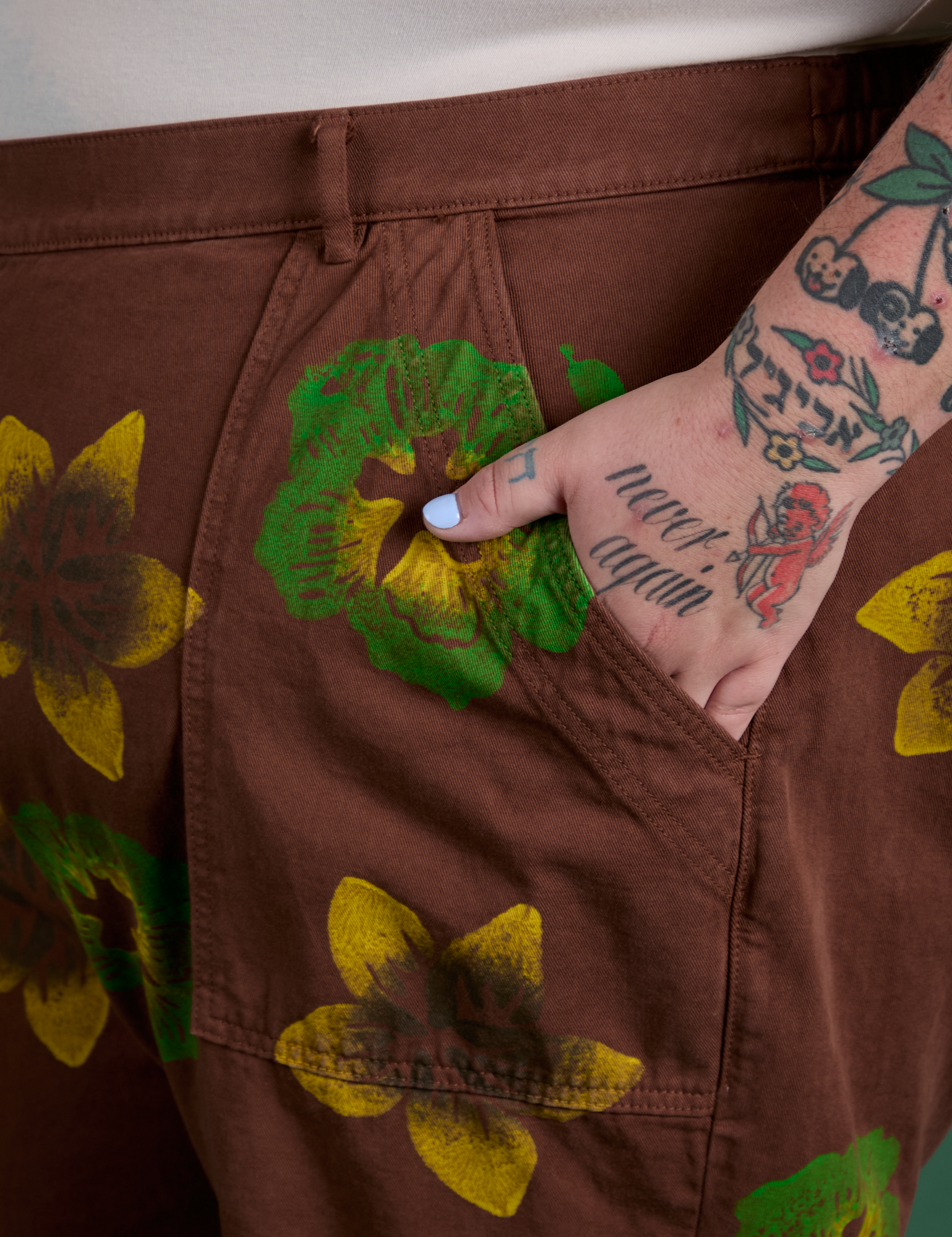 Close up of Sam's hand in the back pocket of Floral Painted Work Pants in Brown
