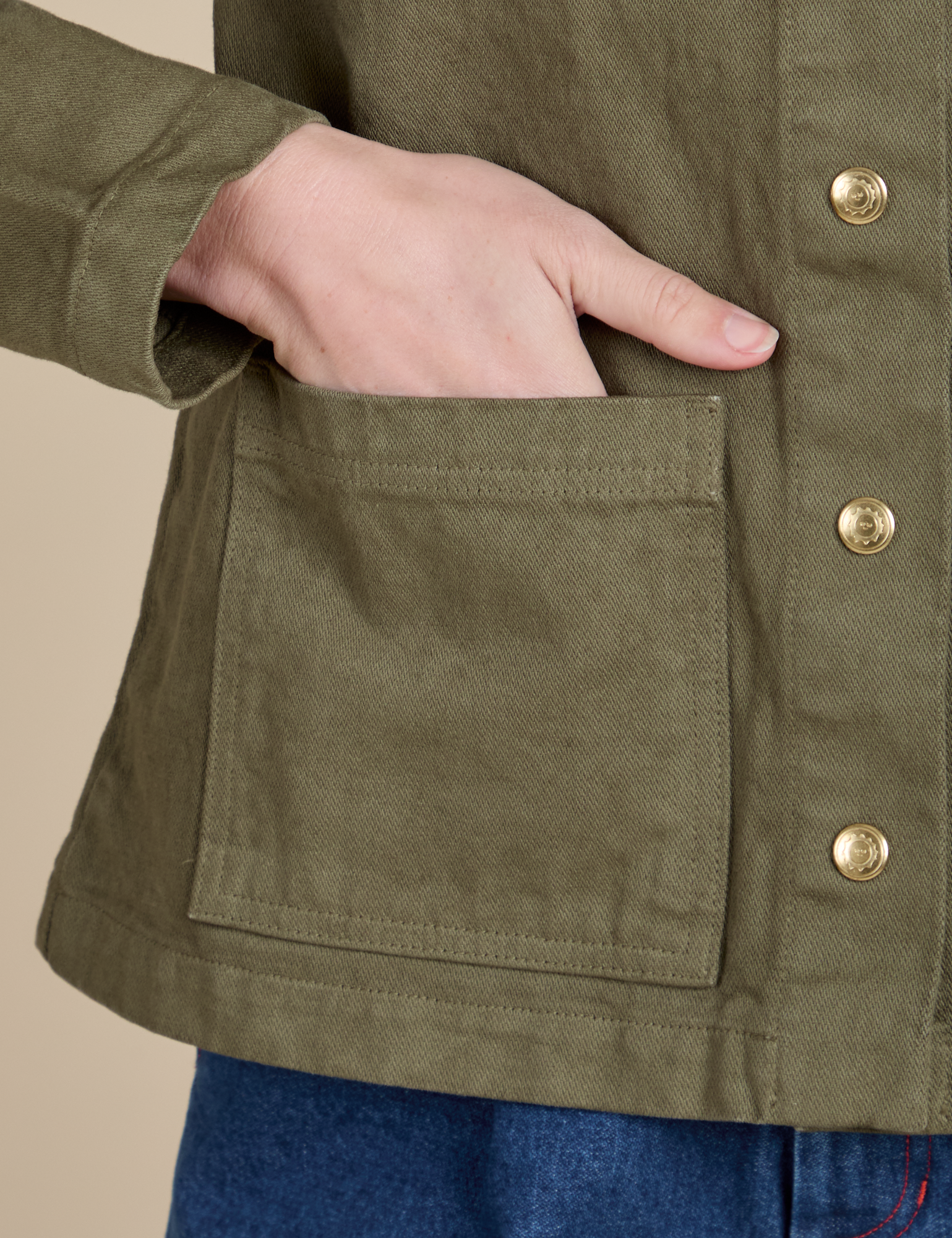 Close up of Alex's hand in the front pocket of Denim Work Jacket in Surplus Green