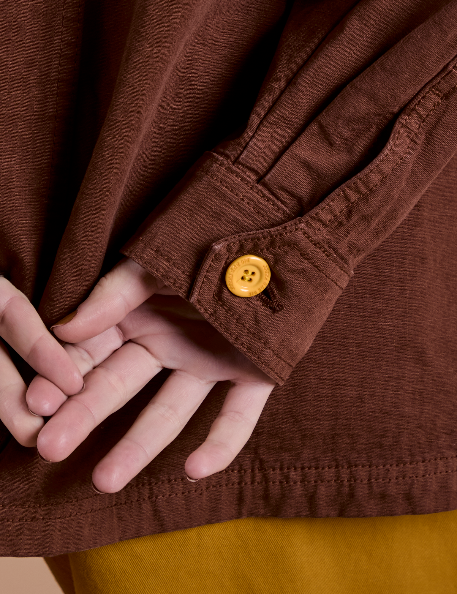 Sleeve close up with yellow button on Ripstop Field Coat in Fudgesicle Brown 