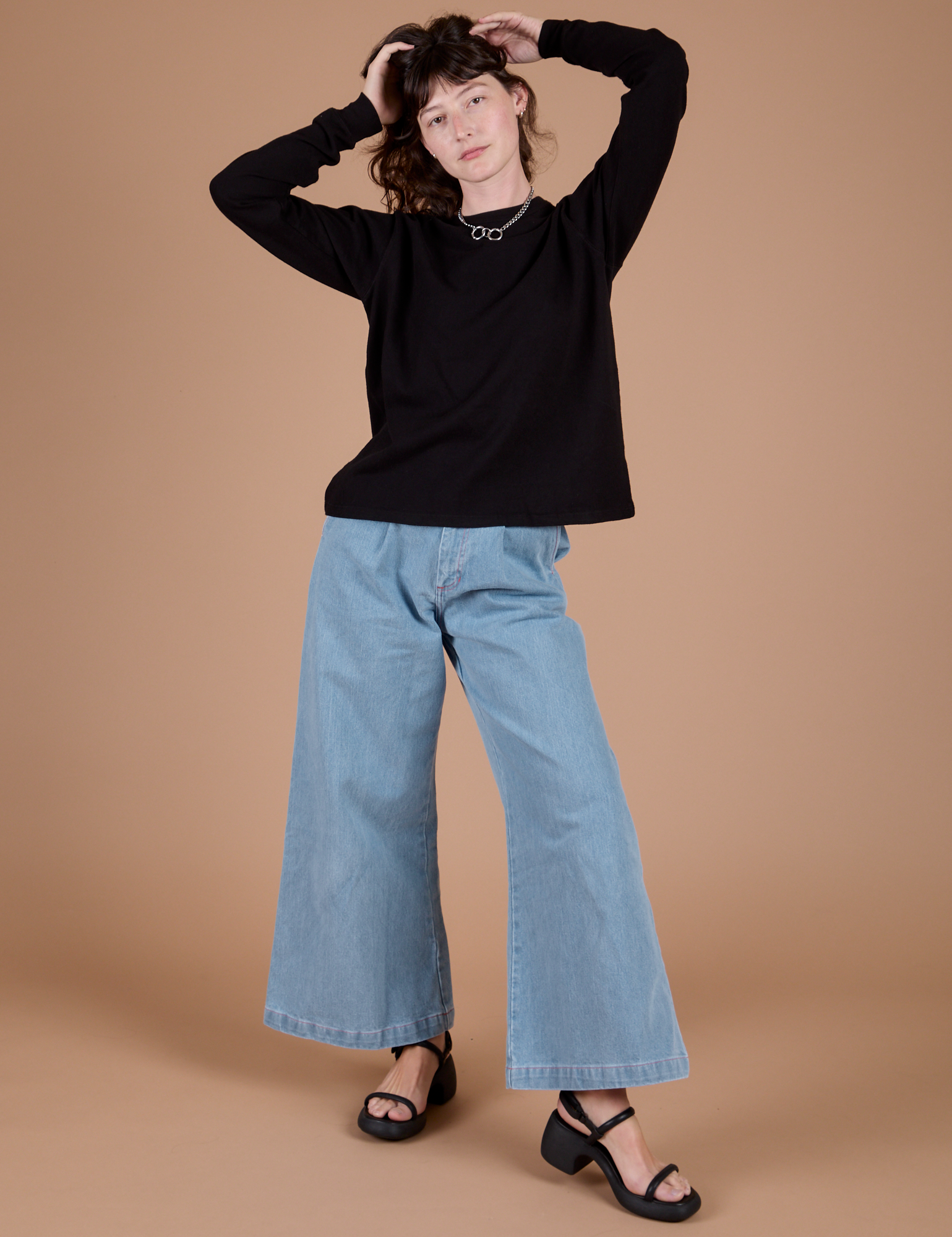 Alex is wearing Long Sleeve Burly Tee in Basic Black with light wash Indigo Wide Leg Trousers