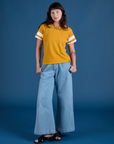 Alex is wearing Painted Burly Tee in Mustard Yellow and light wash Wide Leg Trousers