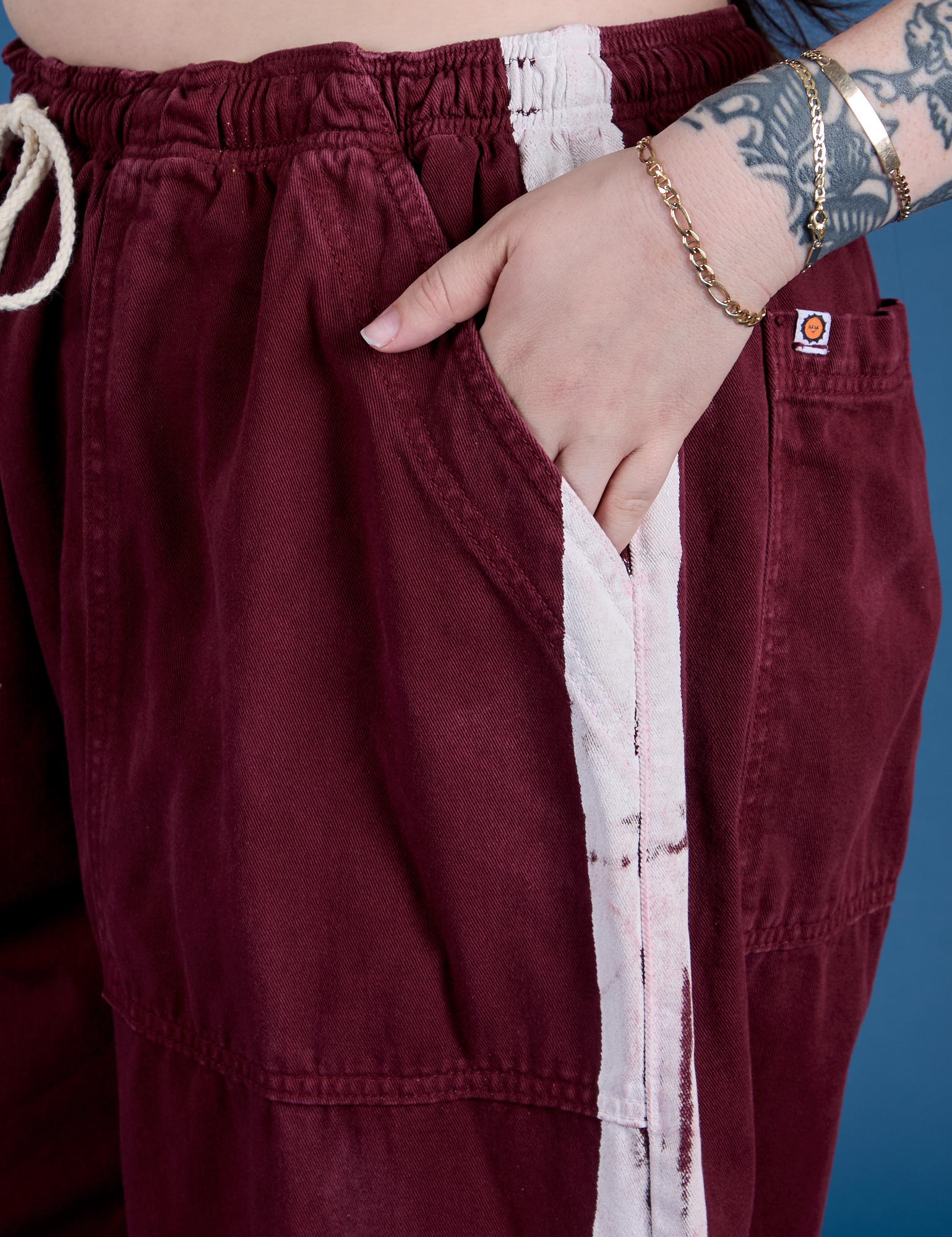 Close up of Sydney's hand in the front pocket of Painted Drop Pocket Cargo Pants in Red Wine