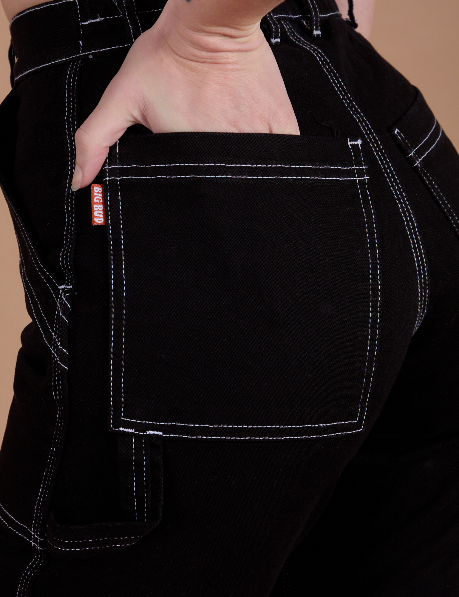 Close up of Alex's hand in the back pocket of Carpenter Jeans in Black