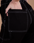 Close up of Alex's hand in the back pocket of Carpenter Jeans in Black