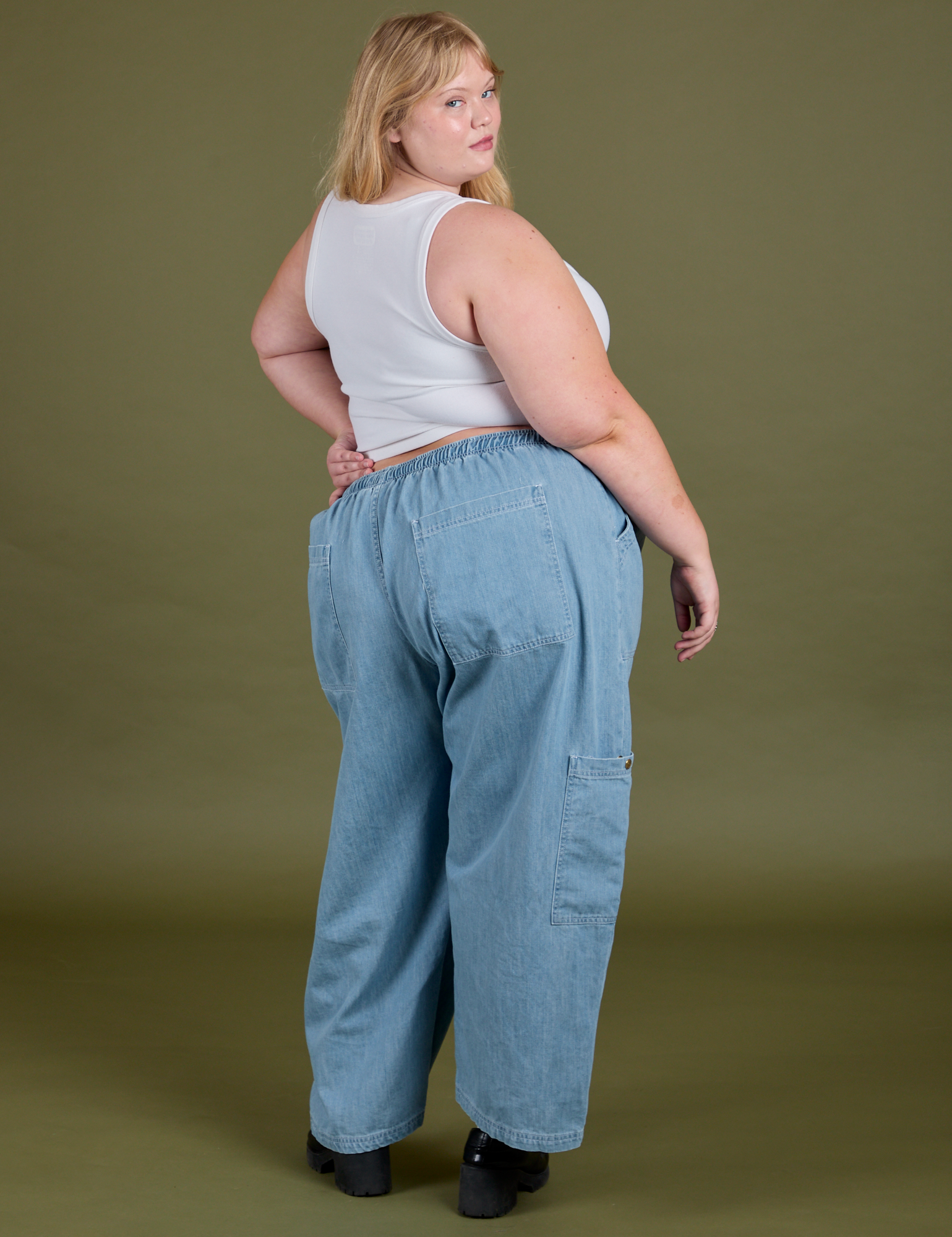 Angled back view of Denim Drop Pocket Pants in Light Wash and Cropped Tank in Vintage Tee White on Juliet
