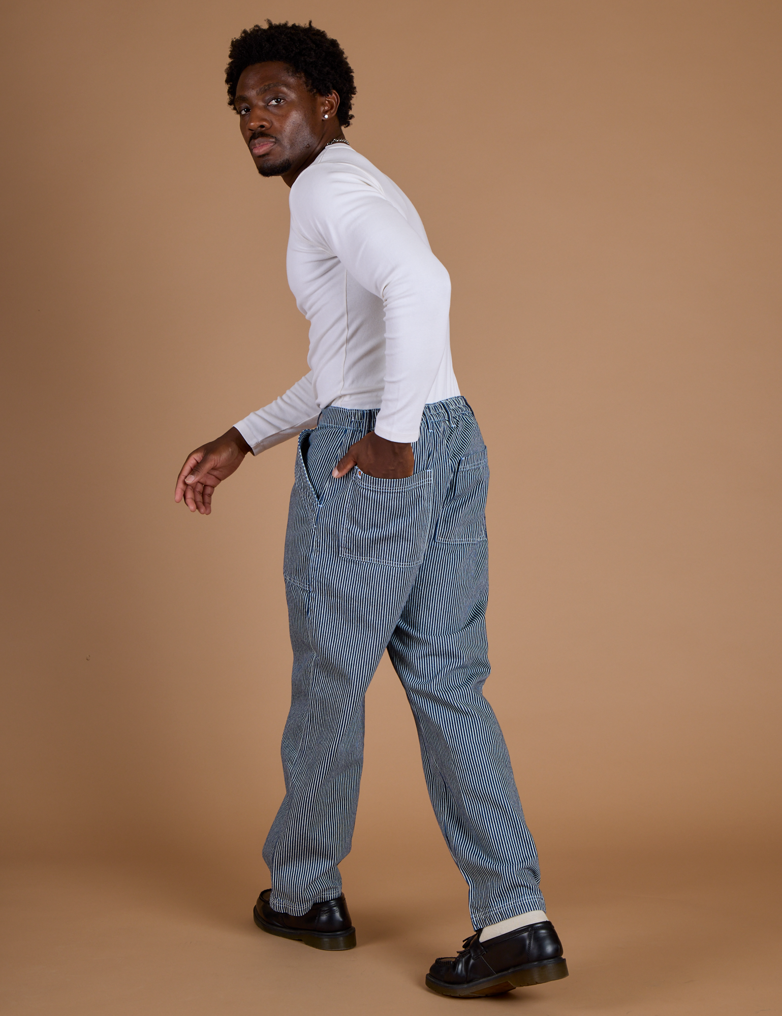 Angled back view of Railroad Denim Work Pants in Natural and long sleeve baby tee in vintage tee white