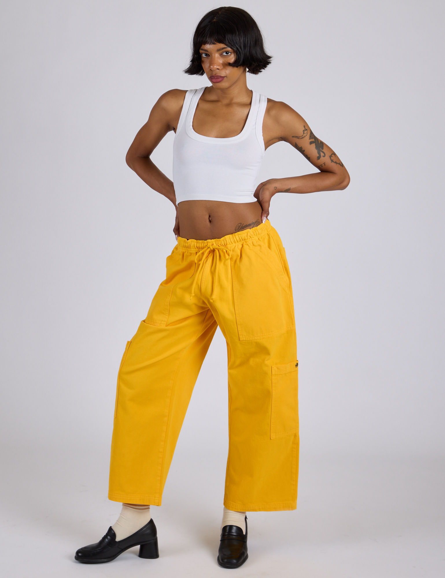 Kira is wearing Drop Pocket Cargo Pants in Sunshine Yellow and vintage tee white Cropped Tank