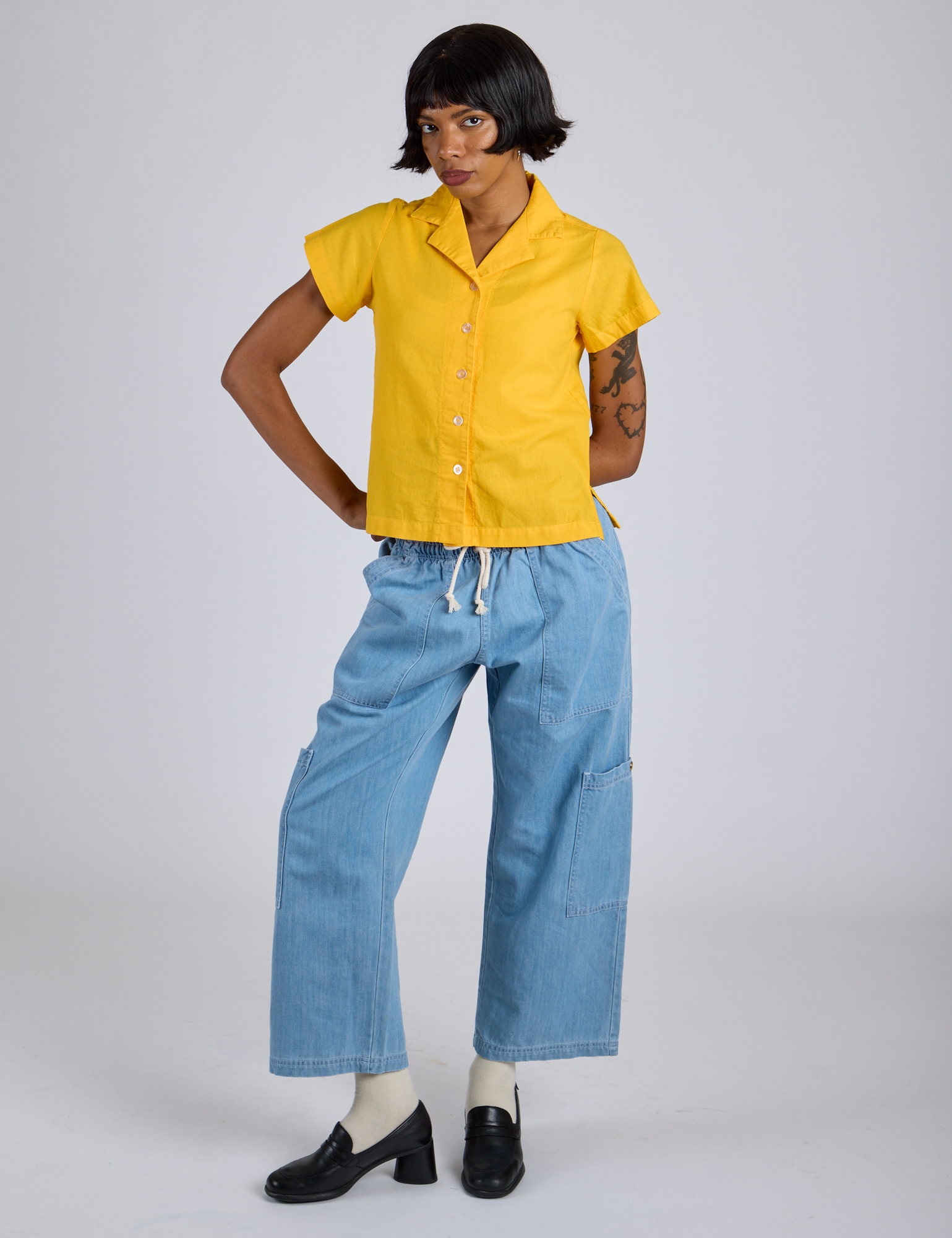 Kira is 5’10” and wearing P Pantry Button-Up in Sunshine Yellow paired with light wash Denim Drop Pocket Pants
