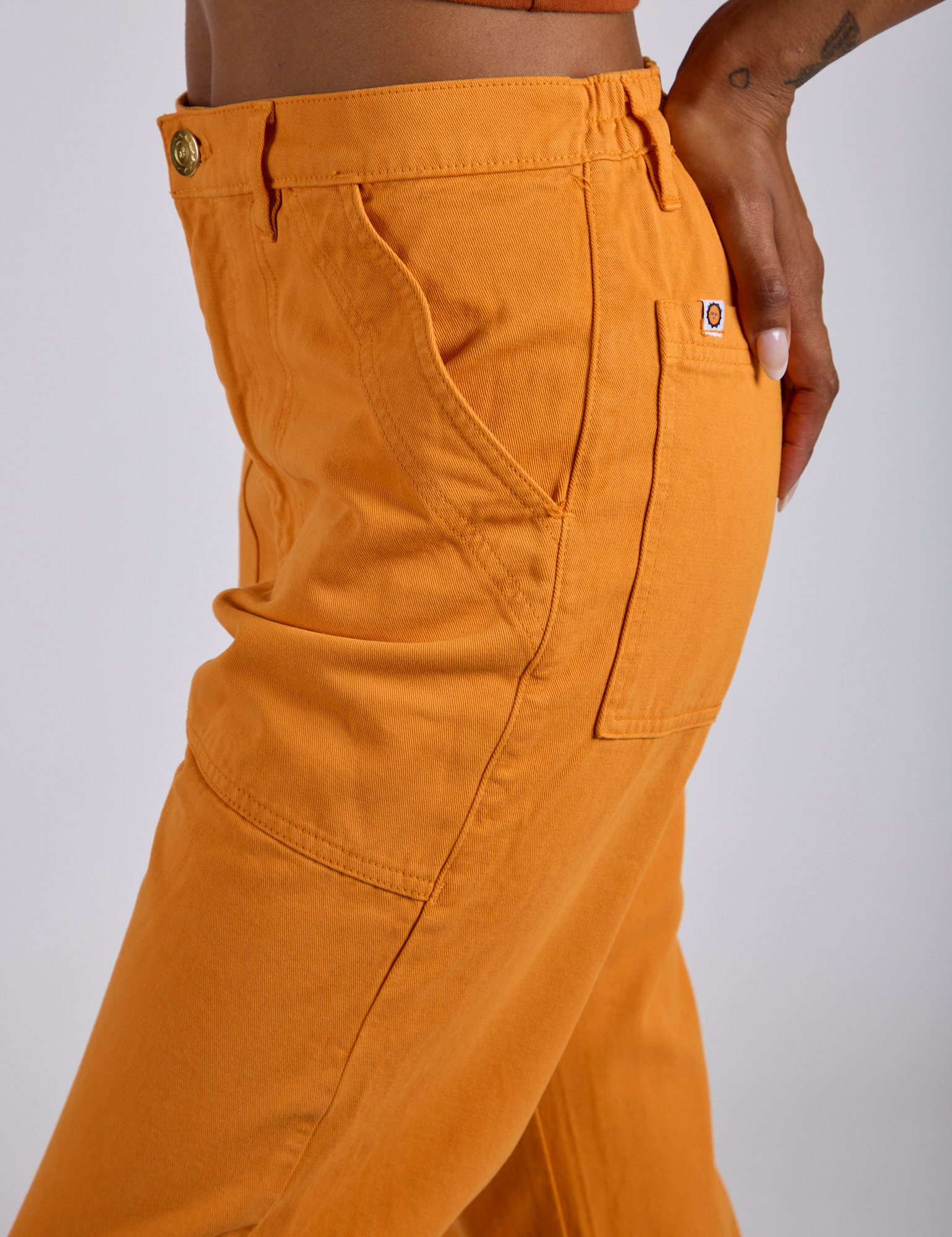 Close up side view of Work Pants in Creamsicle Orange on Kira