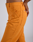 Close up side view of Work Pants in Creamsicle Orange on Kira