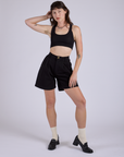 Alex is wearing Pleated Trouser Shorts in Basic Black and Mini Tank in Black