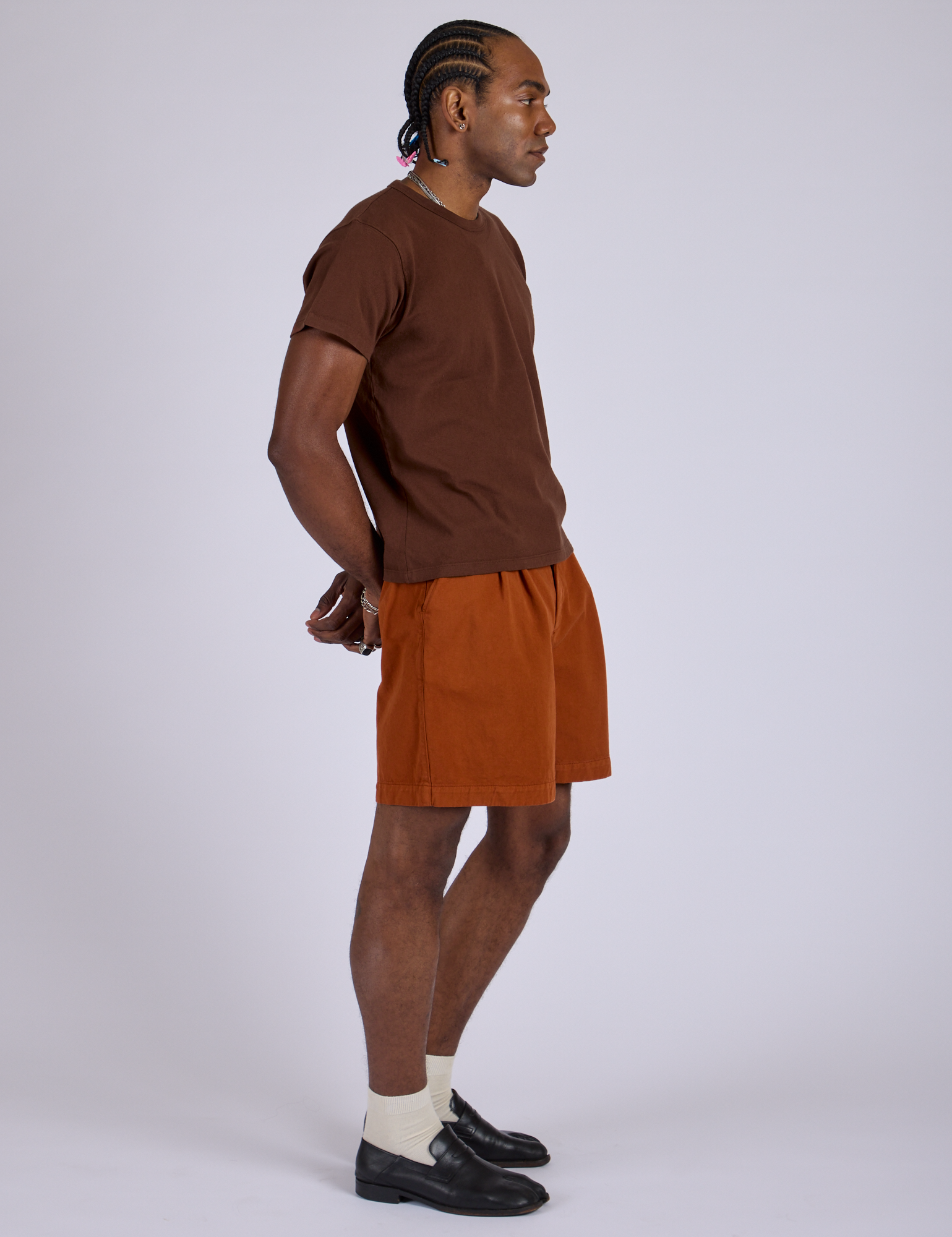 Side view of Pleated Trouser Shorts in Burnt Terracotta and fudgesicle brown Organic Vintage Tee on Jerrod