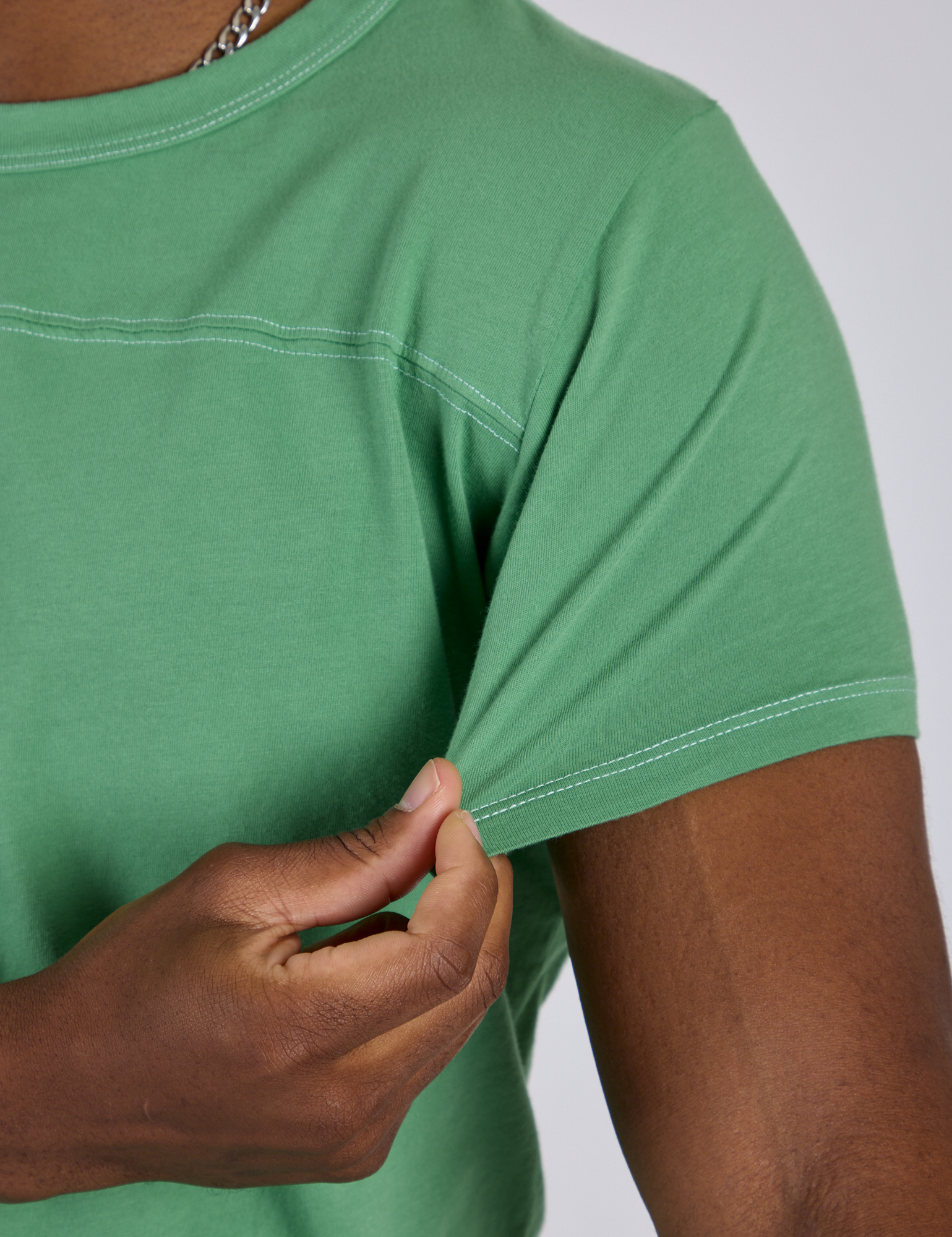 Close up of Isaac tugging the sleeve of Jr. Varsity Tee in Seafoam Green