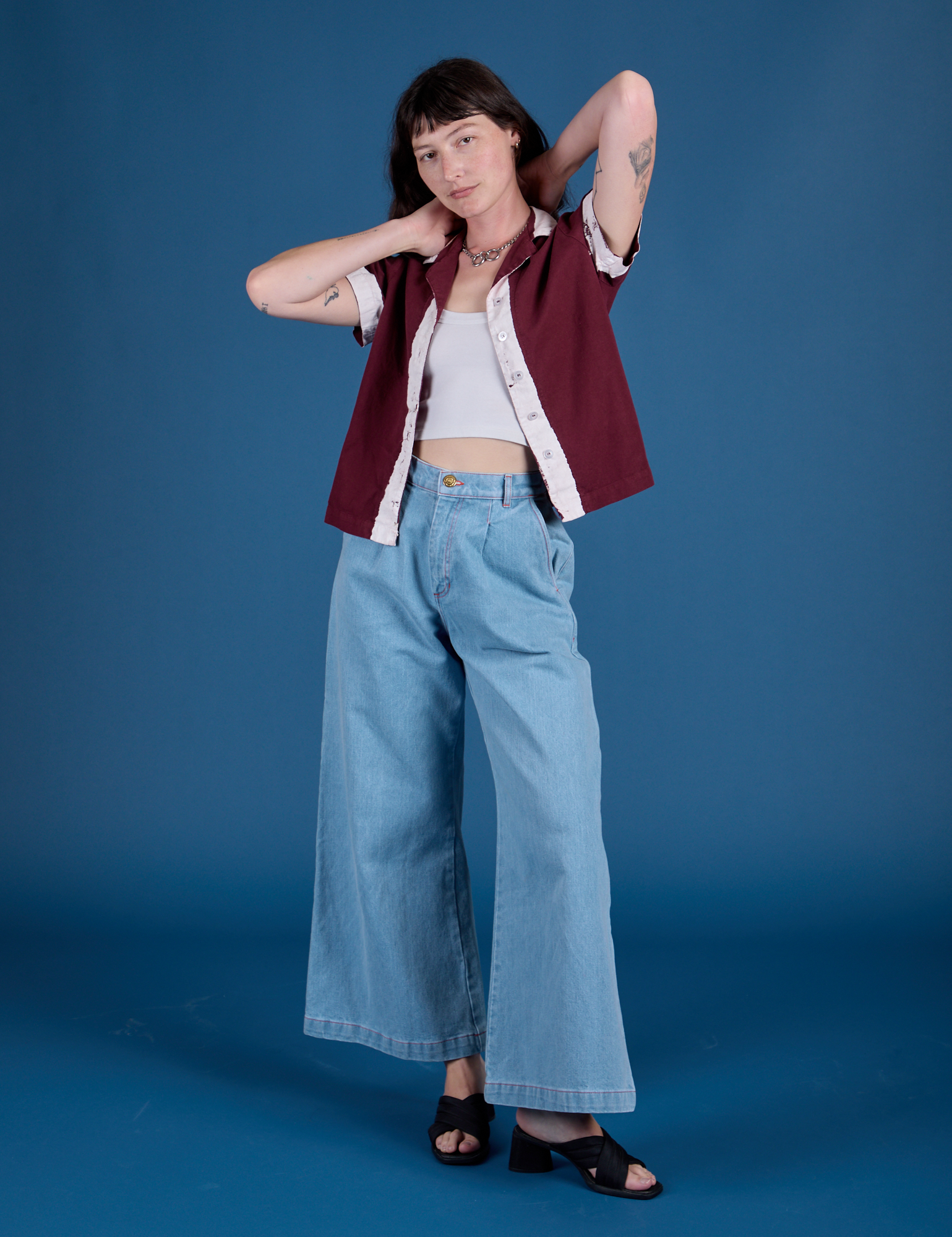 Alex is wearing Painted Pantry Button-Up in Red Wine and light wash Wide Leg Trousers
