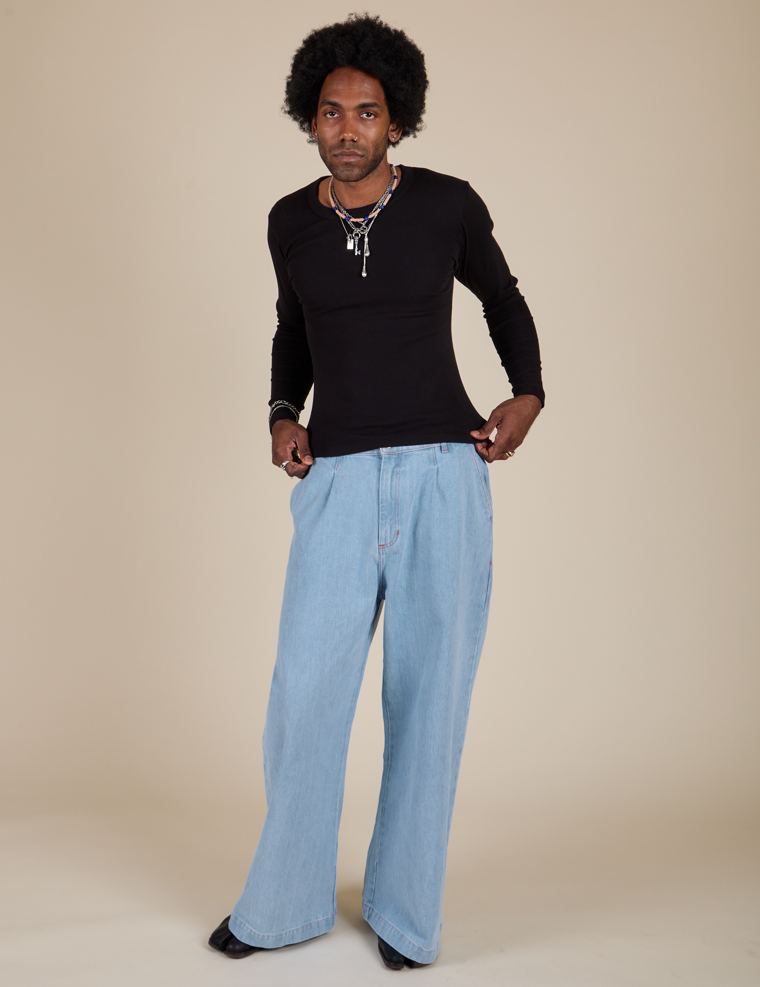 Jerrod is wearing Long Sleeve Baby Tee in Basic Black and light wash Indigo Wide Leg Trousers