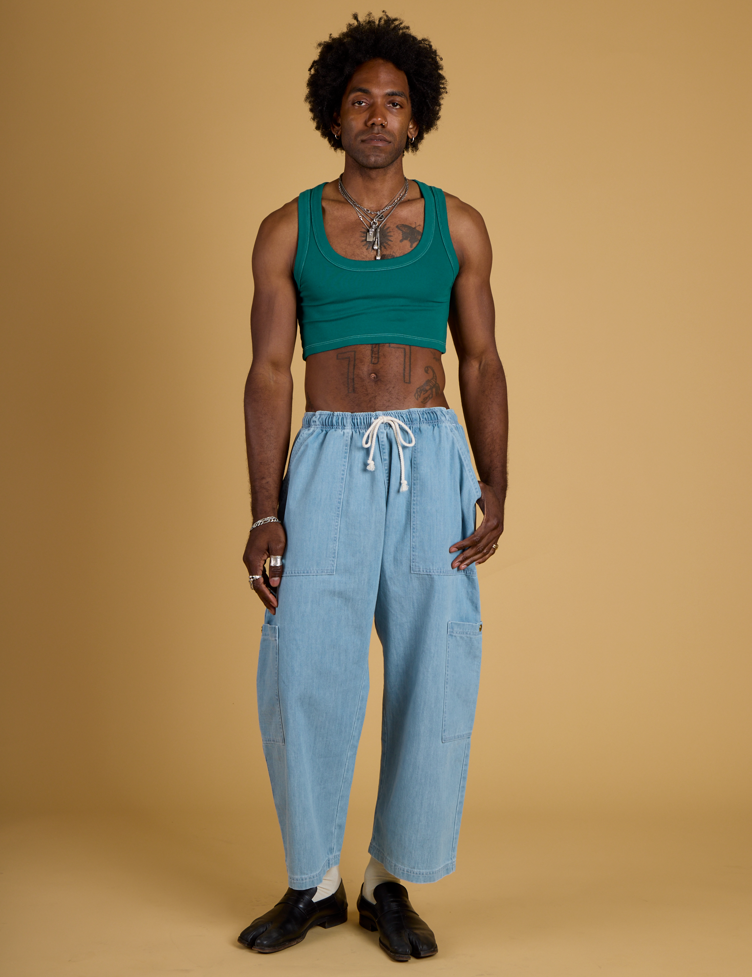 Jerrod is wearing Contrast Stitch Mini Tank in Hunter Green and light wash Denim Drop Pocket Pants