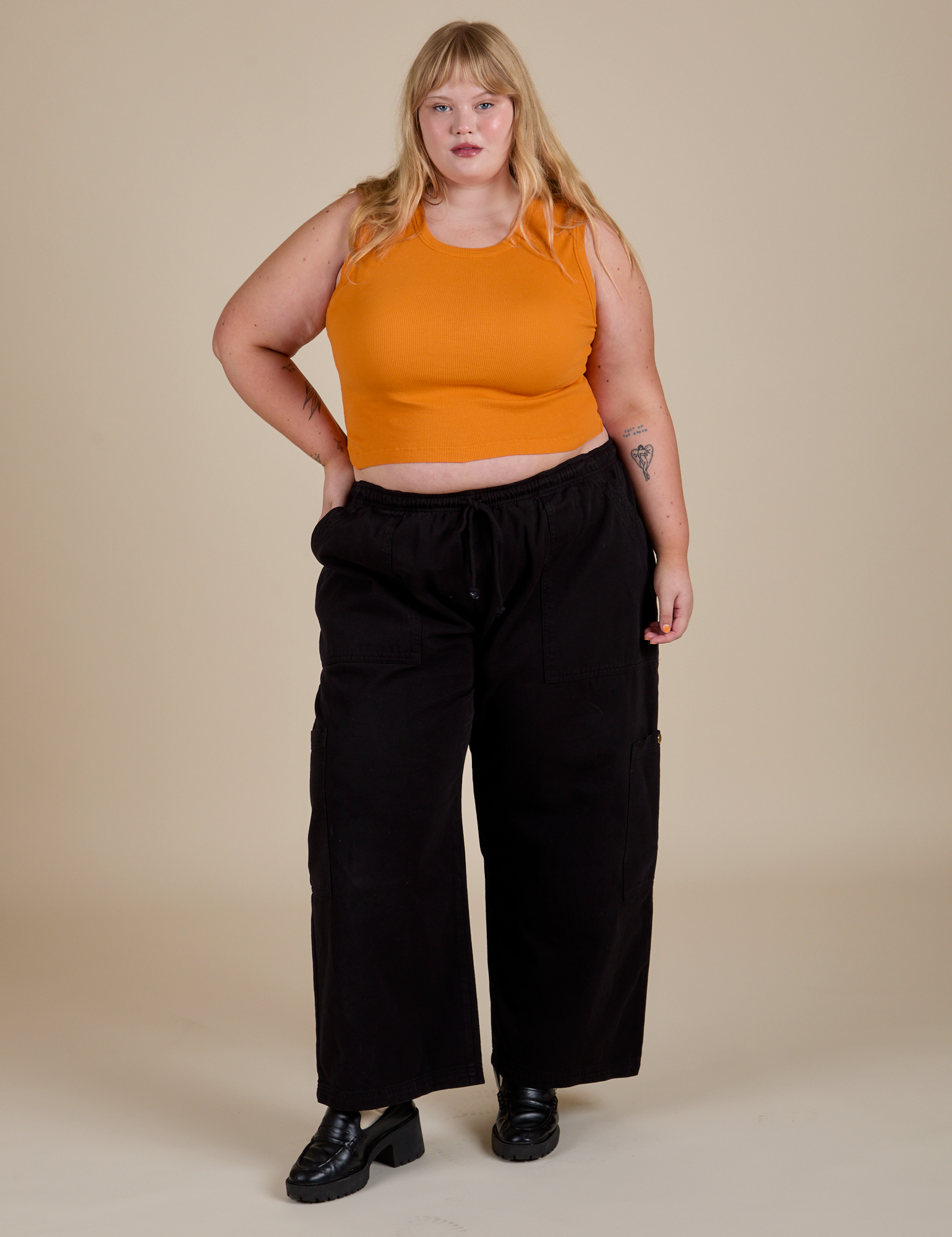 Juliet is wearing  Muscle Tee in Creamsicle Orange and black Drop Pocket Cargo Pants