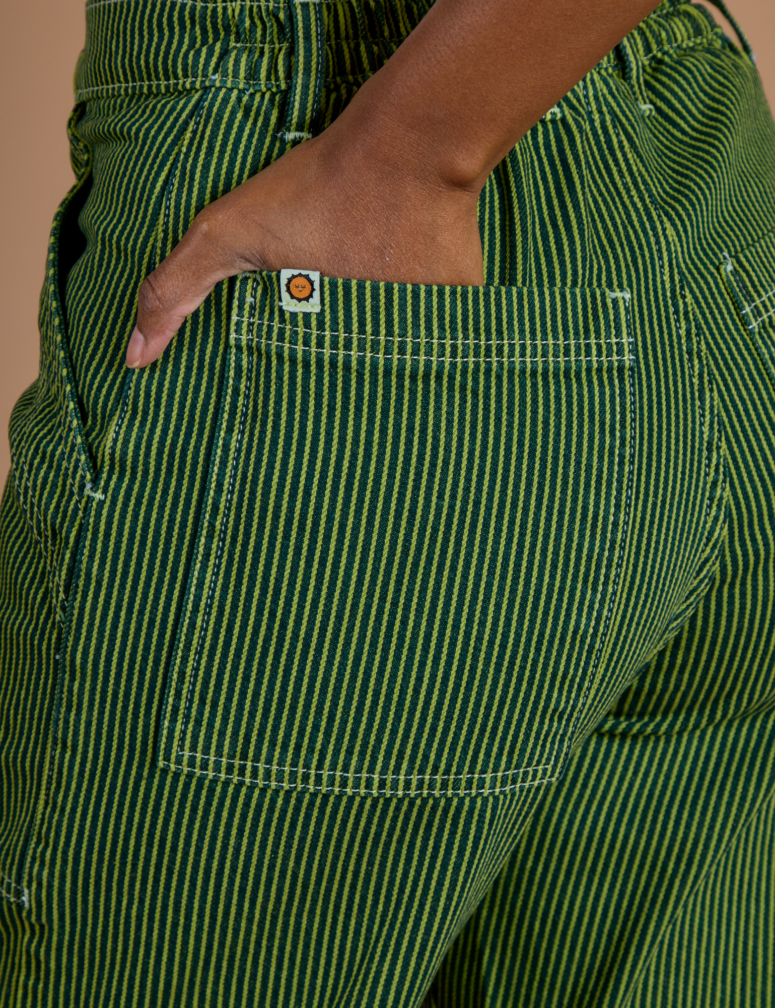 Close up of Kandia's hand in the back pocket of Railroad Denim Work Pants in Gross Green Overdye