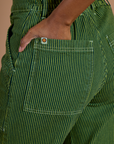 Close up of Kandia's hand in the back pocket of Railroad Denim Work Pants in Gross Green Overdye