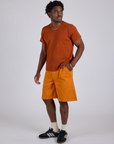 Angled front view of Longline Work Shorts in Creamsicle Orange and burnt terracotta Organic Vintage Tee