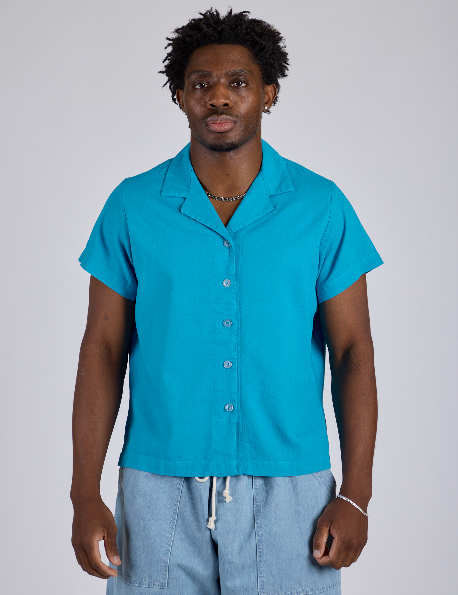 Isaac is wearing a buttoned up Pantry Button-Up in Hawaiian Blue