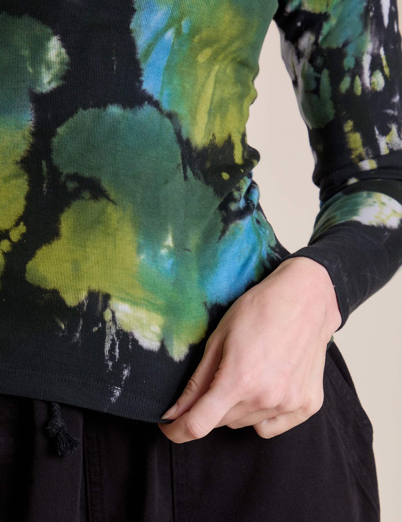 Long Sleeve Baby Tee in Green Pool bottom close up with Alex holding the hem