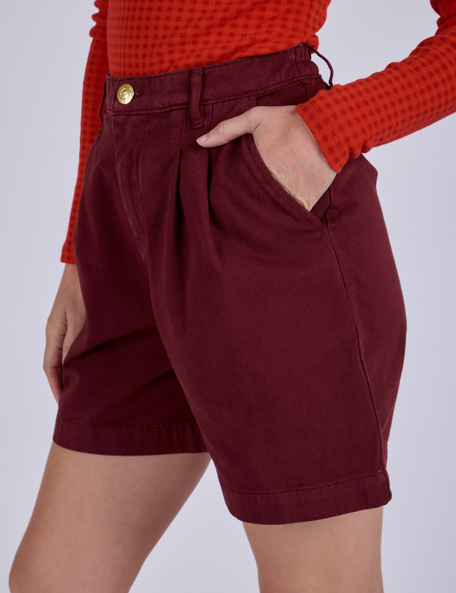 Side view close up with Alex's hand in the front pocket of Pleated Trouser Shorts in Red Wine