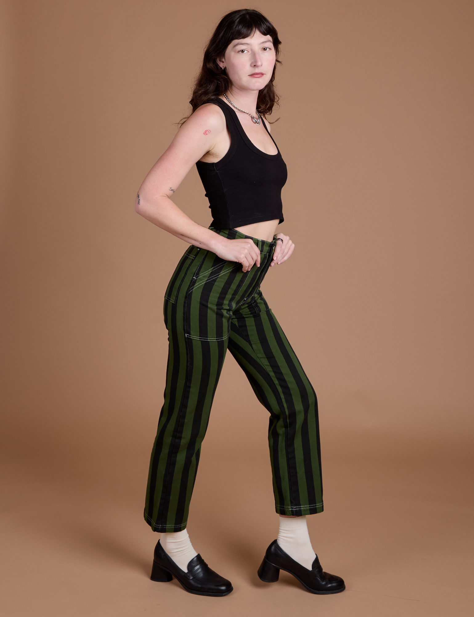 Side view of Black Stripe Work Pants in Evergreen and black Cropped Tank on Alex