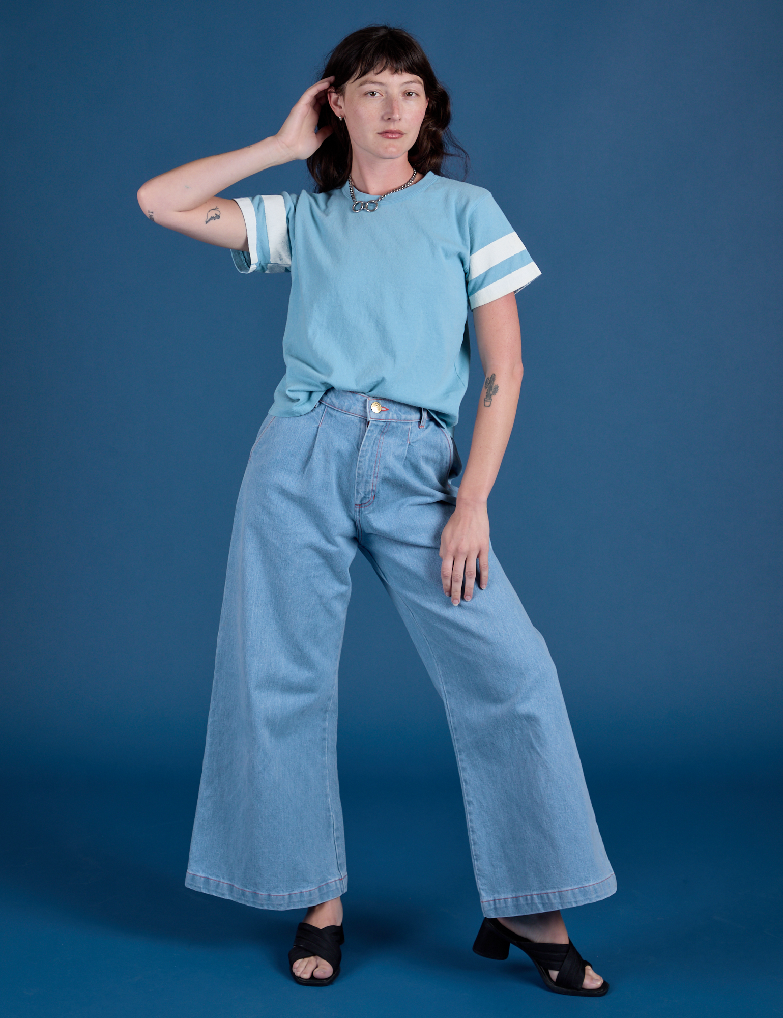 Alex is wearing Painted Burly Tee in Baby Blue and light wash Wide Leg Trousers