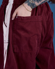 Close up of Sydney's hand in the back pocket of Painted Drop Pocket Cargo Pants in Red Wine