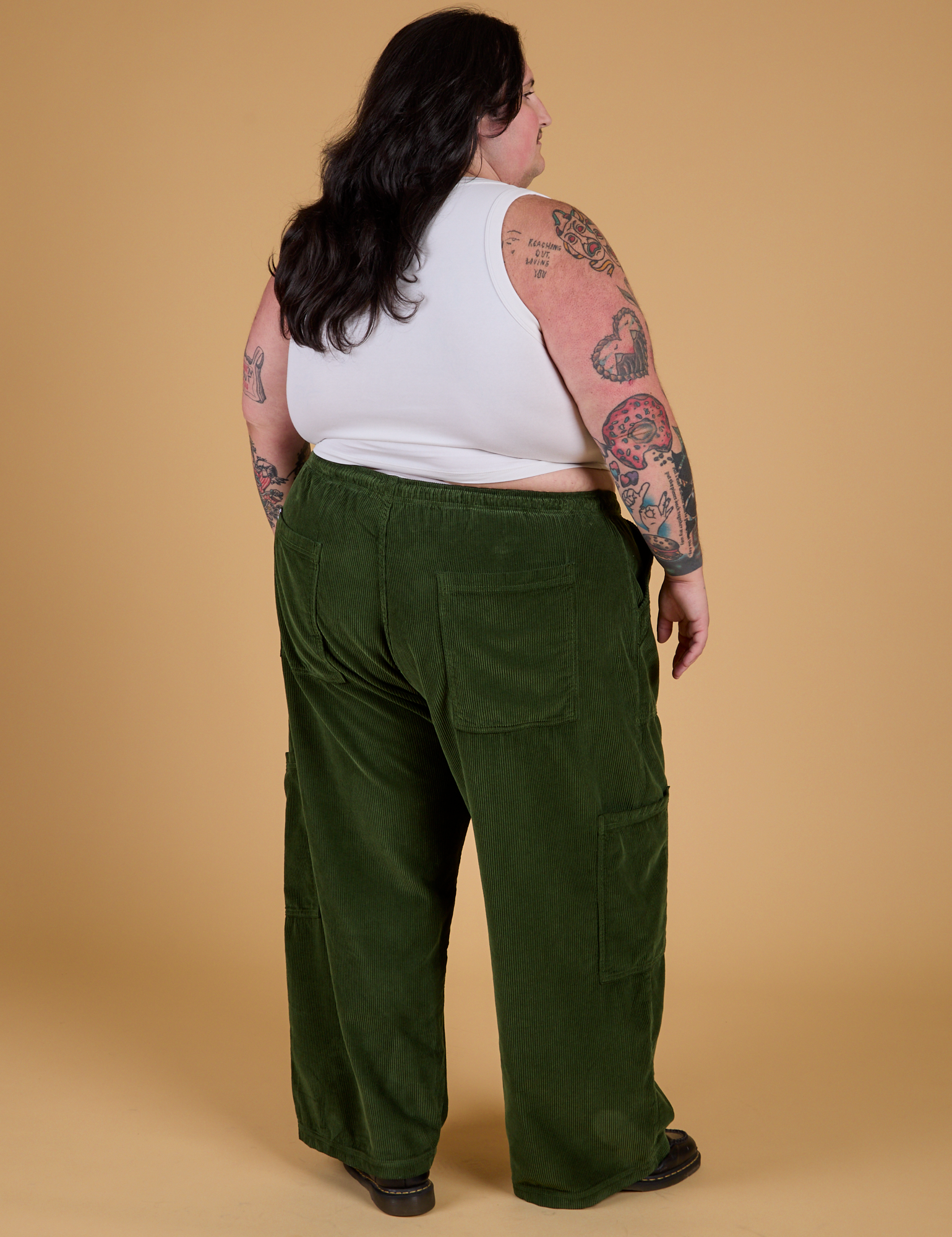 Angled back view of Corduroy Drop Pocket Cargo Pants in Evergreen and Cropped Tank in Vintage Tee White on Sam