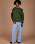 Jerrod is wearing Long Sleeve Burly Tee in Evergreen and light wash Indigo Wide Leg Trousers