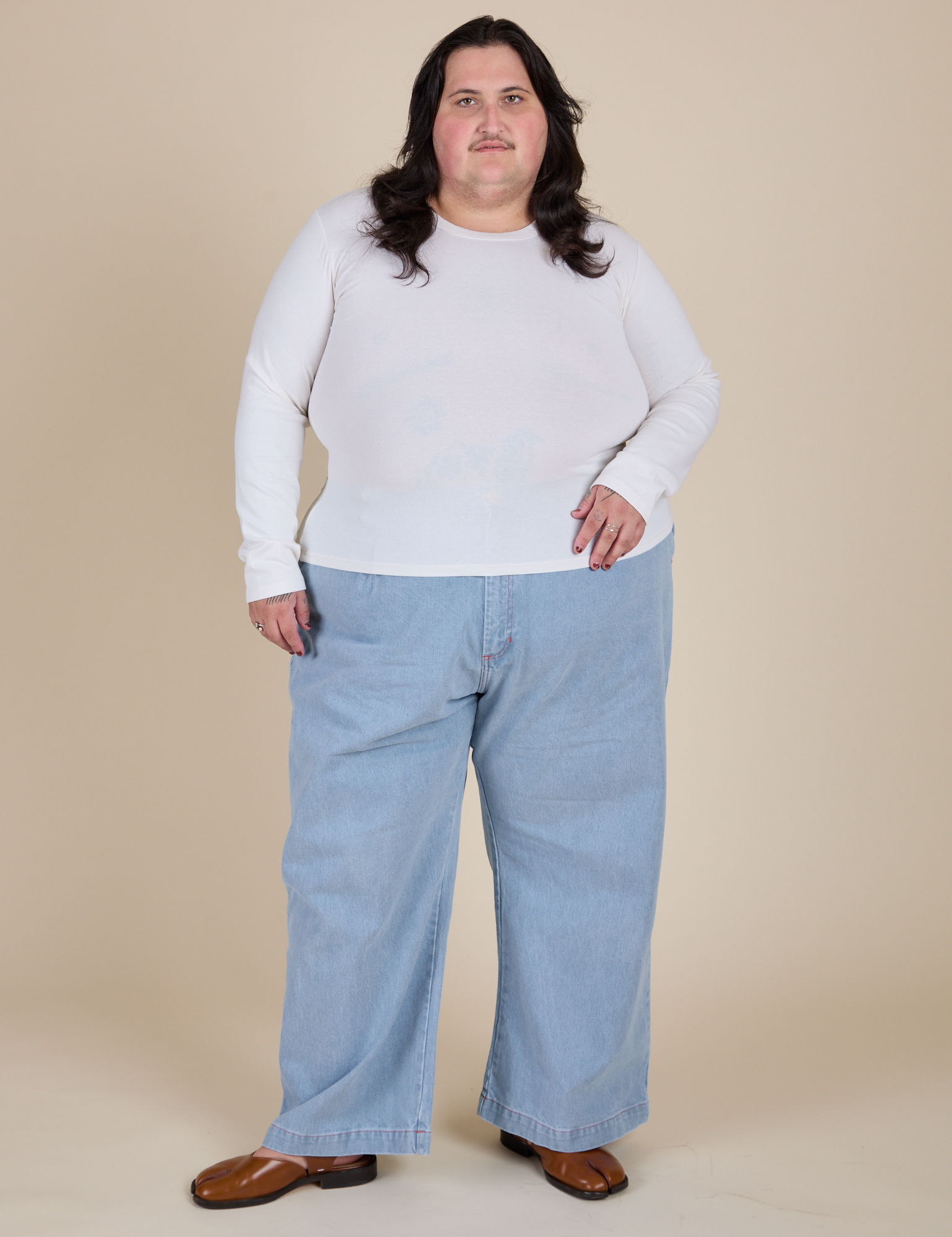 Sam is wearing Long Sleeve Baby Tee in Vintage Tee Off-White  paired with light wash Indigo Wide Leg Trousers