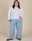 Sam is wearing Long Sleeve Baby Tee in Vintage Tee Off-White  paired with light wash Indigo Wide Leg Trousers