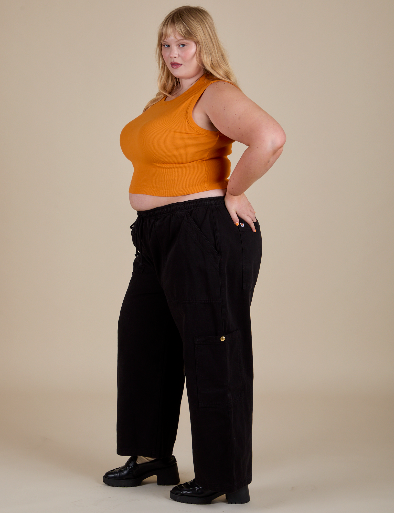 Side view of  Muscle Tee in Creamsicle Orange and black Drop Pocket Cargo Pants on Juliet