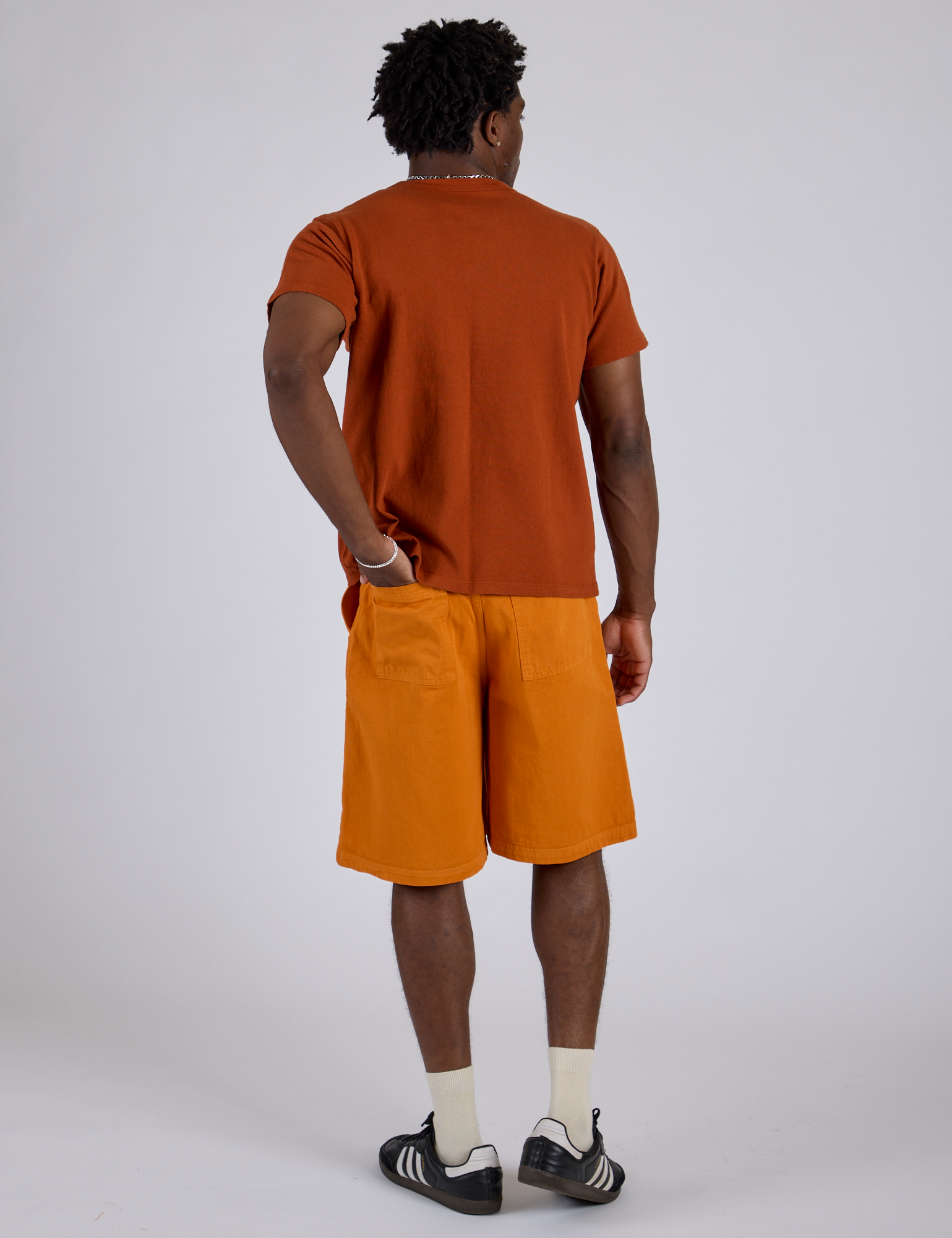 Back view of Longline Work Shorts in Creamsicle Orange and burnt terracotta Organic Vintage Tee on Isaac