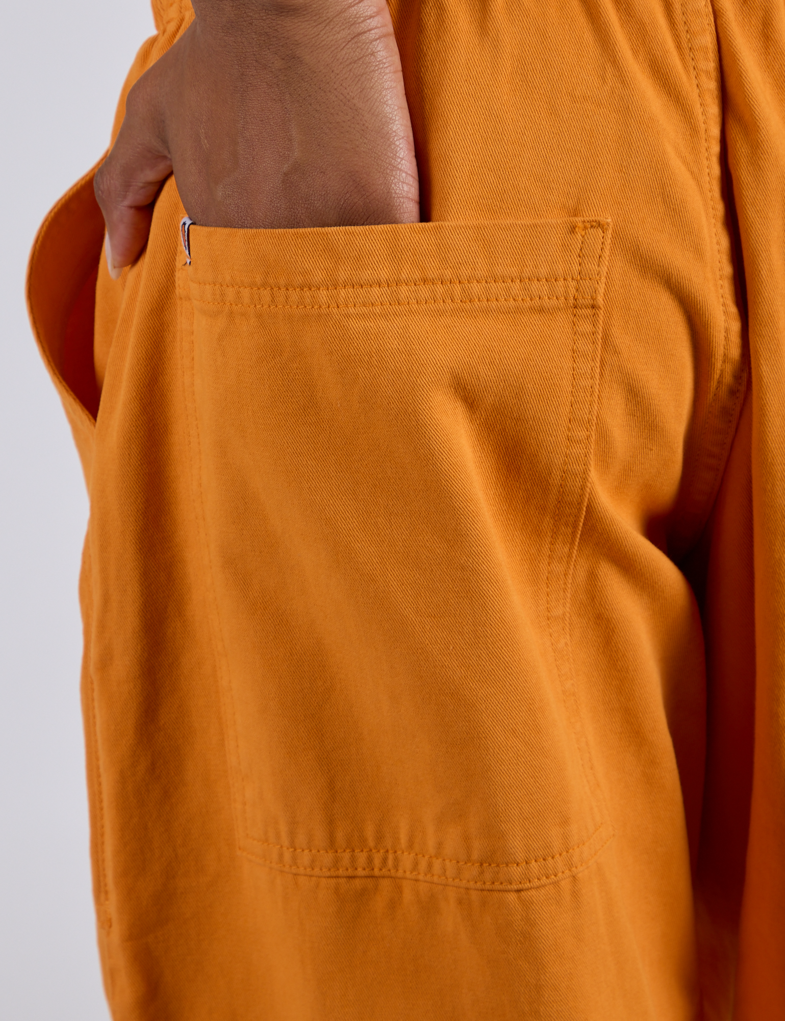 Close up of Kira's hand in the back pocket of Drop Pocket Cargo Pants in Creamsicle Orange