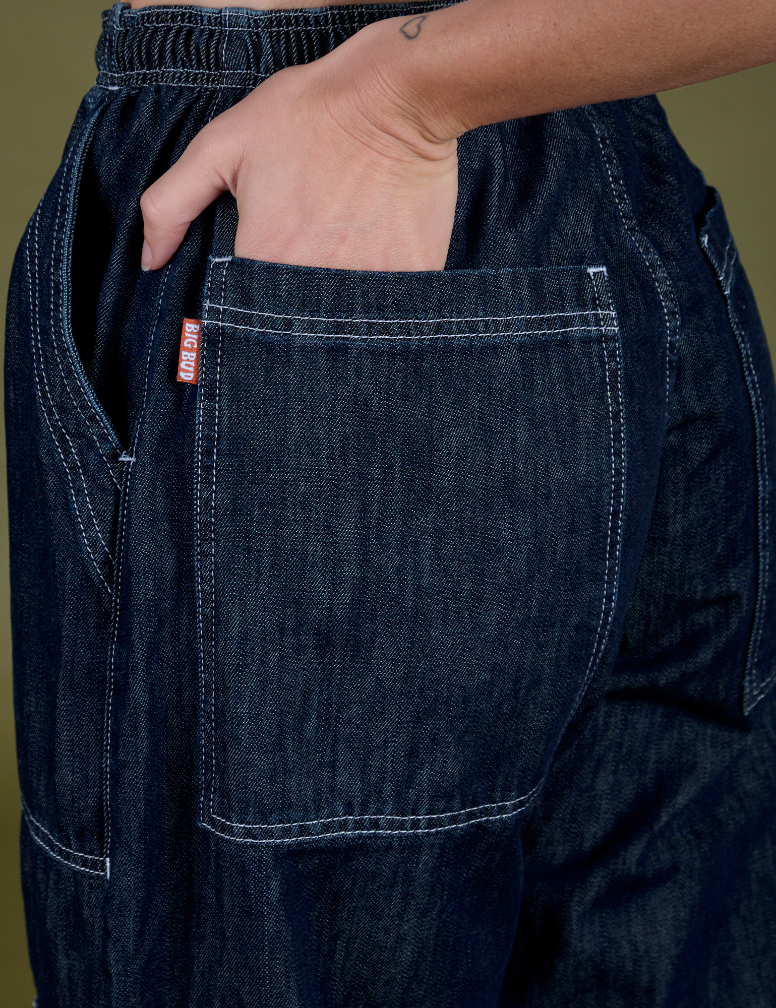 Close up of Alex's hand in the back pocket of Denim Drop Pocket Pants in Dark Wash
