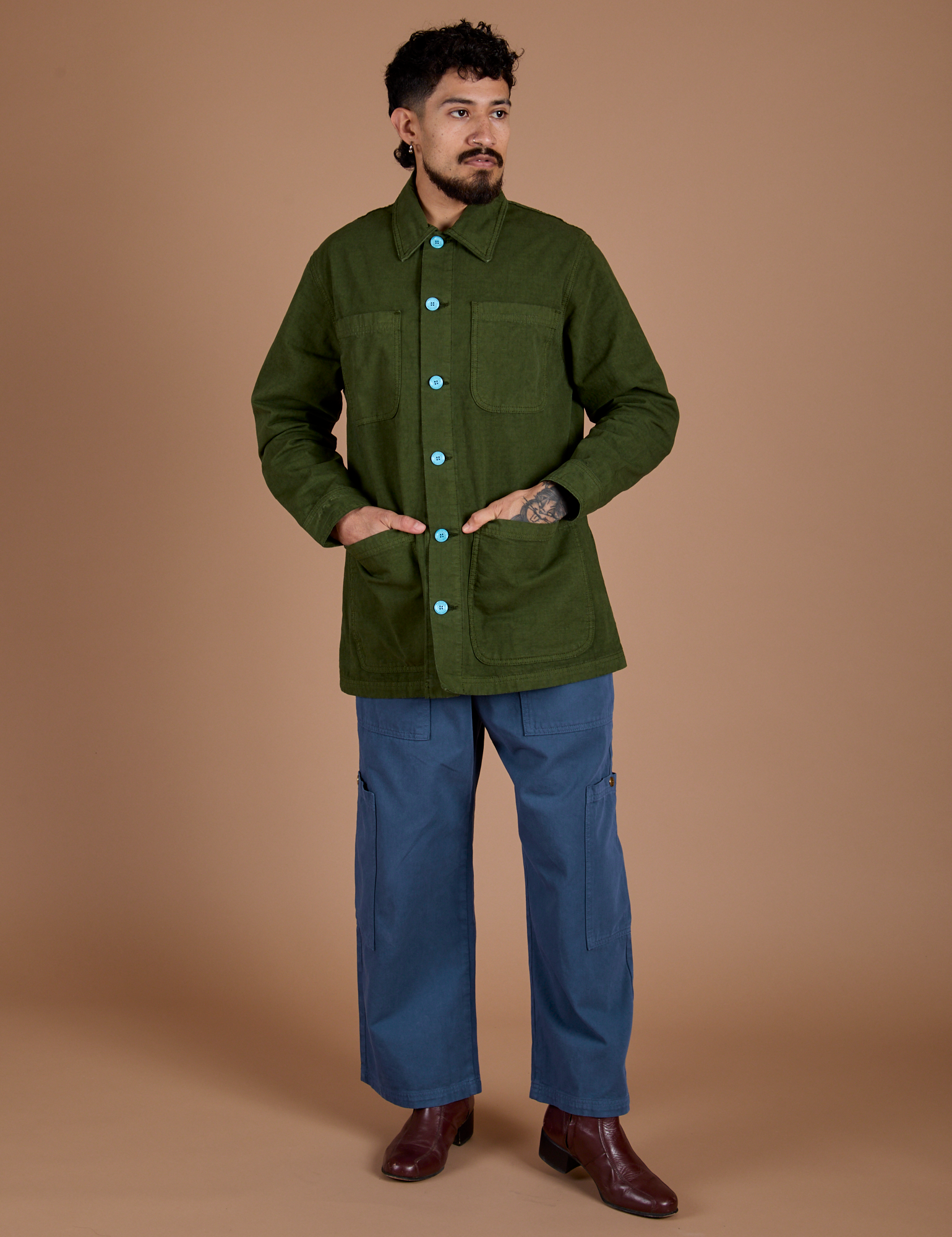 Jesse is wearing a buttoned up Ripstop Field Coat in Evergreen paired with french blue Drop Pocket Cargo Pants