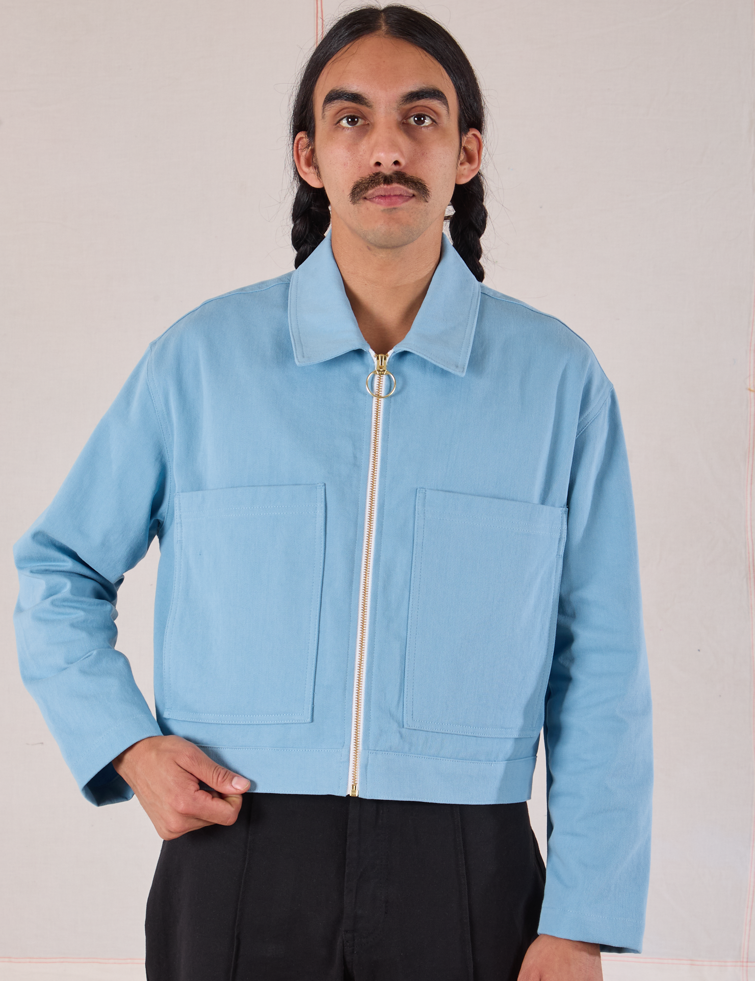 Anthony is wearing a zipped up Mechanic Jacket in Baby Blue