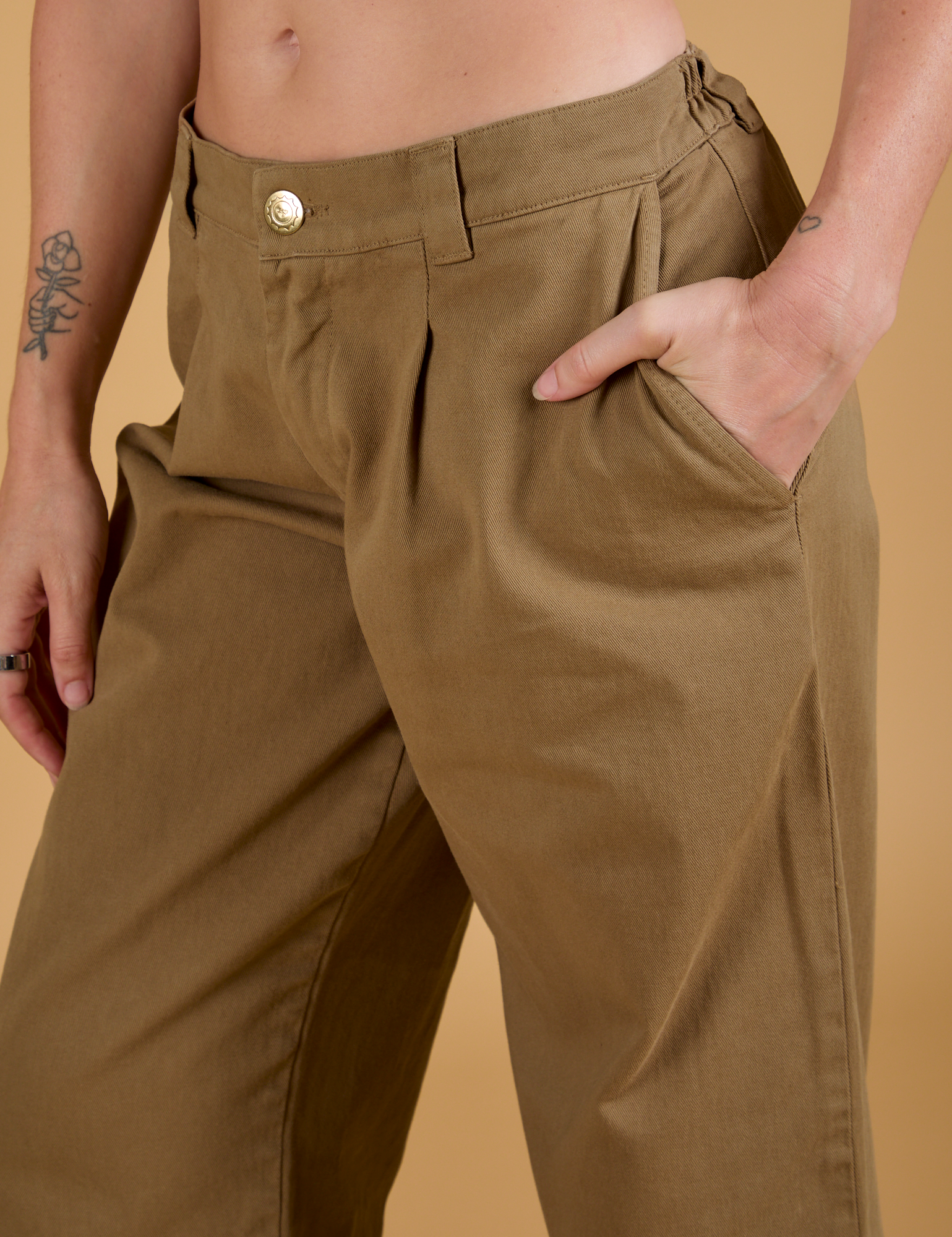 Close up of Alex's hand in the front pocket of Baggy Mid-Rise Trousers in Desert Brown