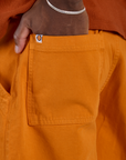 Close up of Isaac's hand in the back pocket of Longline Work Shorts in Creamsicle Orange
